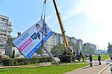Кран поднимает рекламный щит
