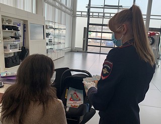 Сотрудница Одинцовской Госавтоинспекции рассказывает посетительнице автосалона о необходимости соблюдения правил дорожного движения